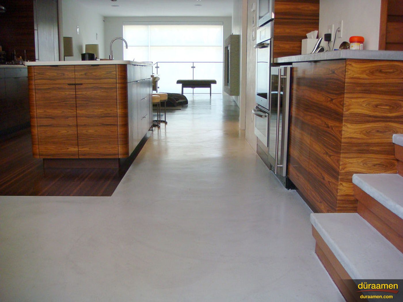 A look through the kitchen of this contemporary residence that has a modern concrete overlay installed as its flooring.