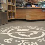 The warm grays in this Skraffino applied concrete resurfacing showcase the logo of this popular NYC coffee shop.