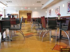 The geometric shapes and warm colors of this cafeteria demonstrate the creative versatility of polished concrete products from Duraamen.