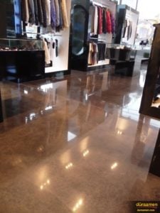 The lights and merchandise reflect on the high shine polished concrete floor in this clothing store.