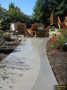 This garden walkway is decorated with an organic curve and two shades of gray. It is a concrete overlay from Duraamen.