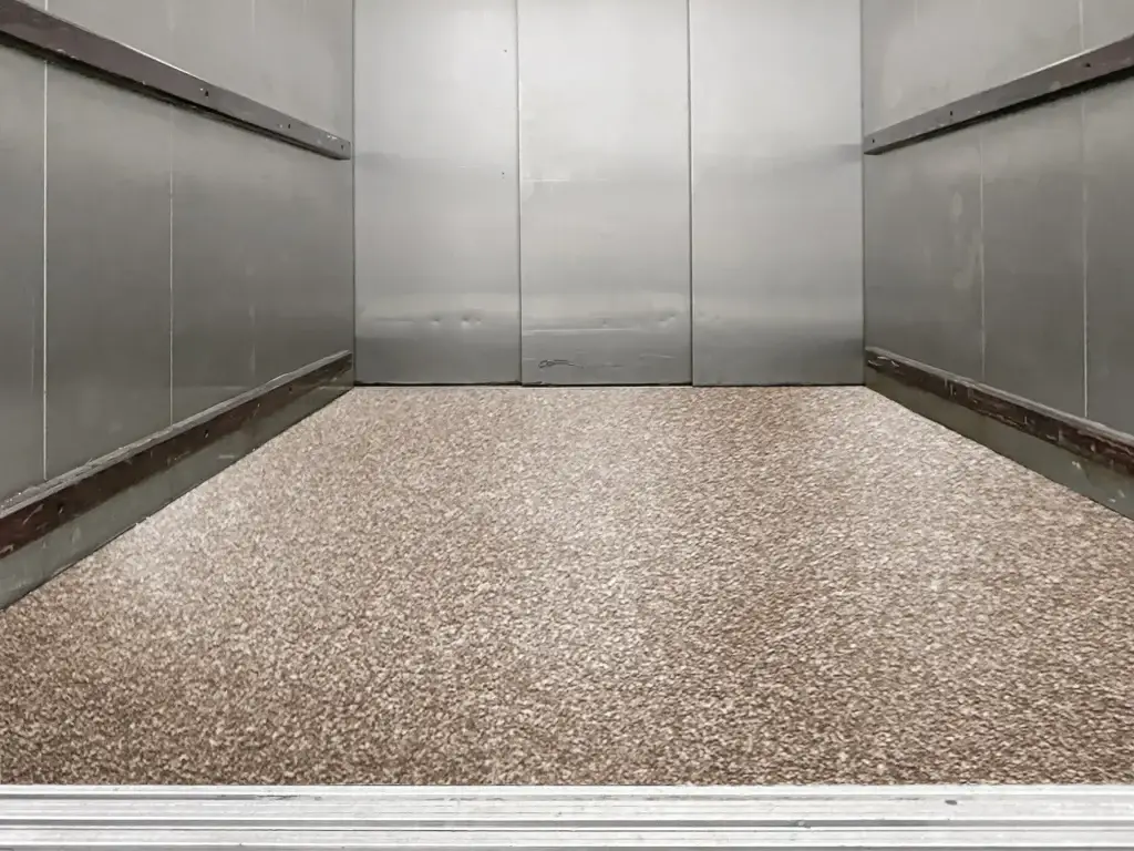 Completed Perdure PU85 freight elevator floor coating with tan and brown Kwortz decorative quartz finish sealed with Perdure P90