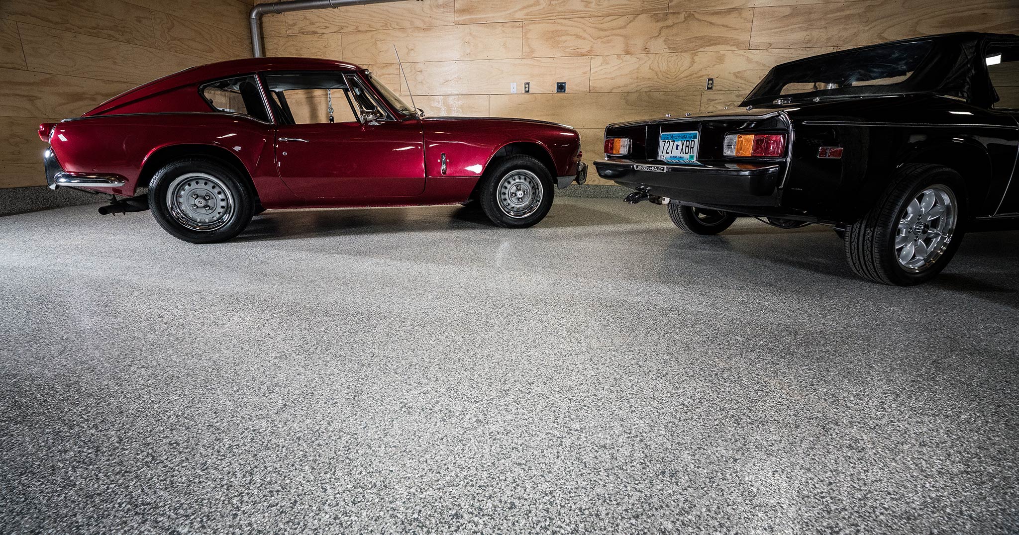 Red sports car parked in a garage with epoxy chip floor coating and non slip surface Endura Vinyl Chip Flooring using Epoxy Polyaspartic Resins | Duraamen Engineered Products Inc