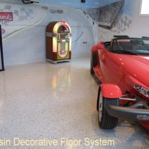 Man cave garage with a red hot rod parked on an epoxy chip floor coating with a non-slip surface.