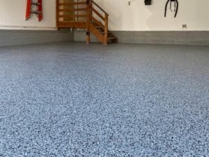 A garage floor coated with epoxy chip floor coating, displaying a mix of differently sized and colored chips.