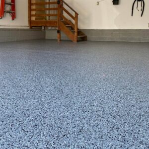 A garage floor coated with epoxy chip floor coating, displaying a mix of differently sized and colored chips.
