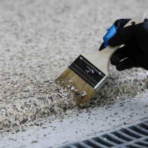 Garage floor with epoxy chip floor coating being applied on the edge of the floor with a brush