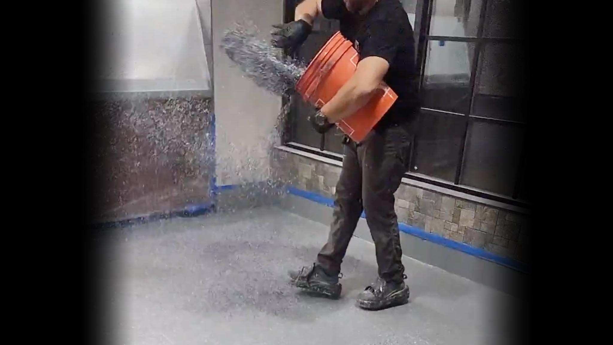 Contractor broadcasting resin chips over an epoxy or polyurea-polyaspartic garage floor.