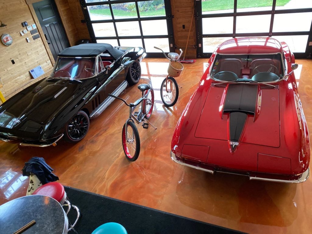 Metallic epoxy garage floor with a red and black corvettes parked