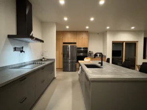 Open kitchen featuring Arapido microcement floors, black appliances, and wood cabinetry.
