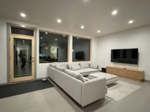 Living room entertainment wall with microcement flooring and wood TV console.
