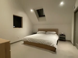 Minimalist bedroom with vaulted ceiling and Arapido microcement floor.