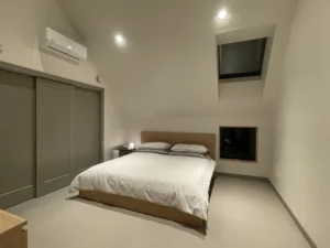 Minimalist bedroom with vaulted ceiling and Arapido microcement floor.
