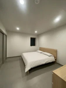 Minimalist bedroom with vaulted ceiling and Arapido microcement floor.