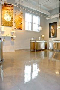 A polished concrete floor with a glossy finish, revealing a subtle pattern of intersecting lines in shades of gray.
