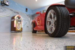 A retro-themed garage with a polished concrete floor showcasing a vintage car, neon signs, and nostalgic memorabilia.